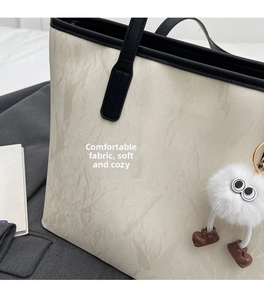 Dettaglio della borsa tote bianco sporco con texture marmorizzata e ciondolo peluche