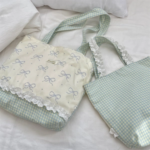 Close-up of light blue canvas tote bag set with lace trim and purple bow pattern detail