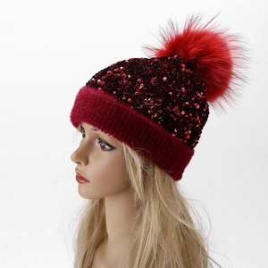 Detail of red sequined knit hat with large faux fur pompom and thick fuzzy lining