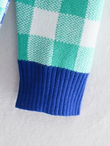 Detail of green and white checkerboard knit sweater with blue ribbed cuff texture