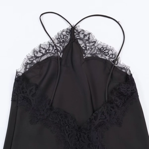 Close-up of black satin camisole featuring delicate lace trim and cross-strap detail