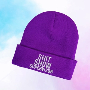 Detailed close-up of the bright purple knit beanie with white embroidered slogan