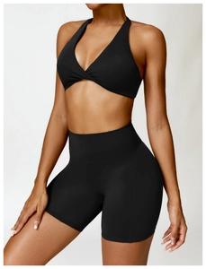 Close-up of black high-waist yoga shorts and cross-knot sports bra with stretch fabric
