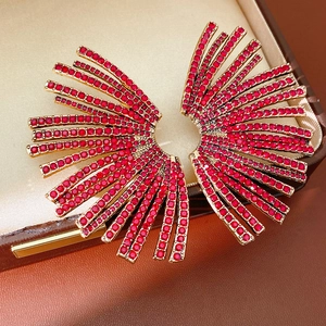 Macro view of gold fan-shaped earrings with red rhinestones in a luxury jewelry box