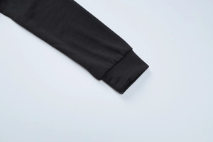 Detalle de los puños acanalados en una sudadera con capucha negra de punto grueso