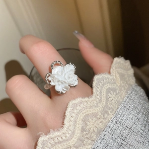 Close-up of elegant white flower ring with silver plating and pearl finish on finger