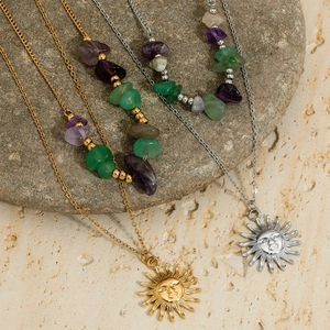 Double-layered sun face pendant necklaces with natural stones on a rustic stone background