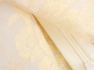 Macro view of mesh fabric with gold glitter floral patterns and invisible zipper detail