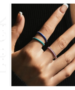 Close-up of three colorful enamel s925 silver rings with zircons worn by a model