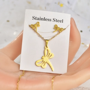 Golden stainless steel dragonfly necklace and earrings set held on a display card
