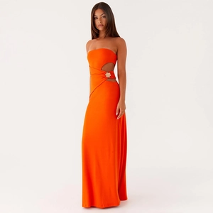 Detalle de vestido palabra de honor naranja con corte lateral y hebilla de flor dorada