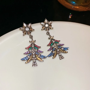 Macro shot of silver needle Christmas tree earrings with pearls and colorful crystals