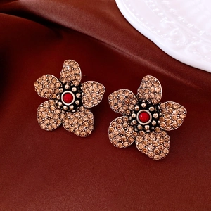 Macro shot of vintage crystal flower earrings on luxury silk with gold petals