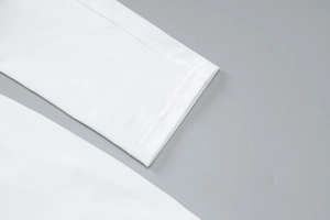 Detailed macro view of white long sleeve cuff showing high-quality fabric texture and stitching