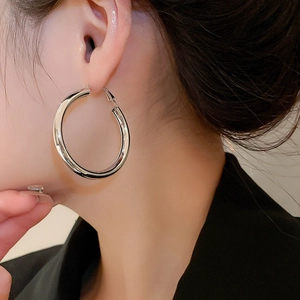 Polished silver hoop earring close-up on model showing the large circular metallic design