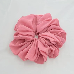 Close-up of a soft pink chiffon scrunchie showing detailed fabric texture and pleats
