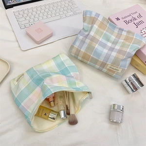 Detailed view of plaid cosmetic bag with metal zipper and soft pastel grid pattern