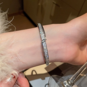 Détail d'un bracelet nœud en argent serti de zircons scintillants porté au poignet
