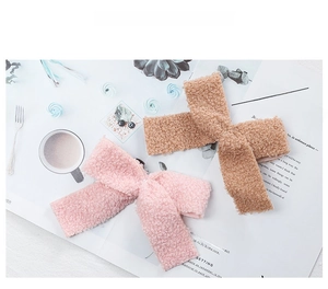 Detailed close-up of pink and beige teddy fleece bow hair bands on a styled table