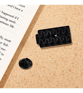 Detailaufnahme einer schwarzen Emaille-Anstecknadel mit geometrischem Muster auf Kork