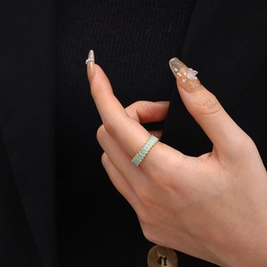 Detail of adjustable gold ring featuring emerald cut light green zircons on a model