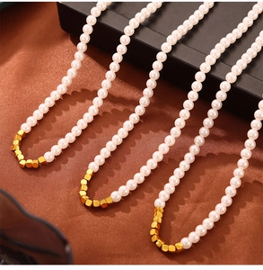 Macro shot of elegant white pearls and gold square metal beads on a brown silk background