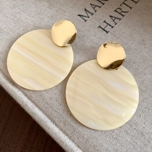 Close-up of vintage cream marbled resin earrings with gold metal disc studs