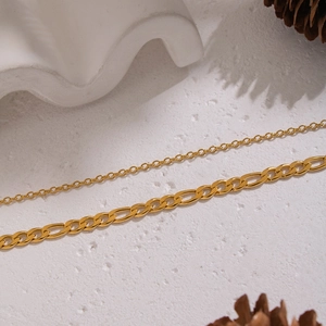 Close-up of golden double-layer chain necklaces on a white textured background