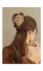 Detail view of a large beige rose fabric hair claw clip on model brown long hair