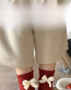 Detail of red wool crew socks featuring a cream knitted bow decoration for women