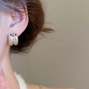 Polished silver teardrop earrings on model showing smooth metallic finish and modern C-shape