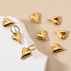 Set di ciondoli e orecchini a cuore in oro lucido su sfondo di pietra minimalista