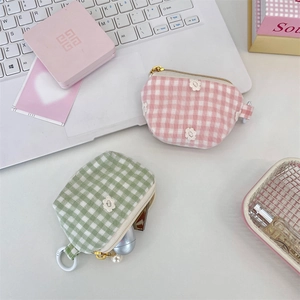 Close-up of pink and green checkered cosmetic pouches with flower pearls and white hooks