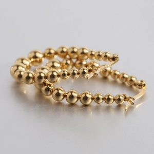Detail of 23mm 18K gold-plated U-shaped beaded hoop earrings with polished finish