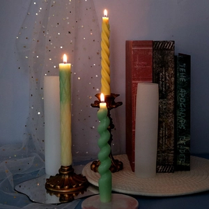 Candele lunghe a spirale e geometriche con luce d'atmosfera su libri d'epoca