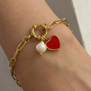 Stainless steel gold bracelet with red enamel heart and white pearl charms on wrist
