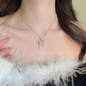 Detail of a golden butterfly necklace with green gemstone and zircon on a female model