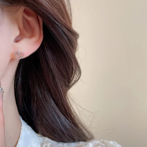 Detailed close-up of a silver heart-shaped earring worn by a model in soft lighting