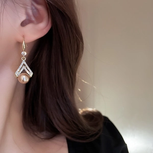 Close-up of elegant triangular gold earrings with sparkling crystals and pearl drop details
