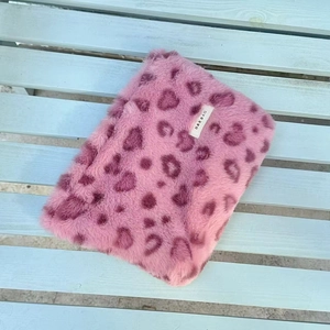 Detail view of pink leopard faux fur cosmetic bag with soft plush texture and brand label