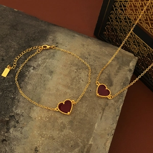 Gold-plated jewelry set with red resin heart pendants on a necklace and bracelet