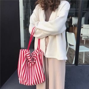 Detailed street style shot of red and white striped large canvas tote bag on shoulder