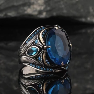 Macro shot of vintage silver ring with oval sapphire stone and ornate scale texture