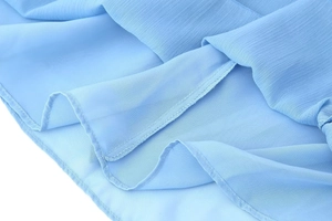 Detailed macro view of sky blue tiered dress fabric with soft pleated chiffon texture