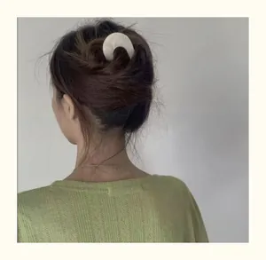 Detail of a white marble pattern acetate U-shaped hair pin styled in a French bun