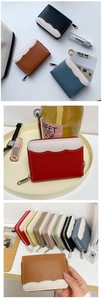 Detail showing various colors of lychee grain leather zip wallets with wavy stitching