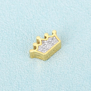 Golden crown pendant with sparkling crystals on light blue textured background