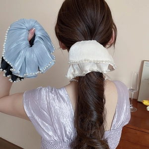 Detail of elegant satin scrunchies with white pearls on blue and white fabric