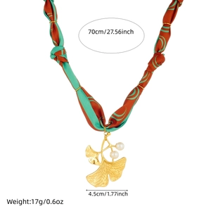 Detail view of gold ginkgo leaf pendant with pearls and green ribbon including dimensions