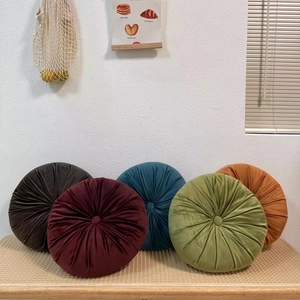 Set of 5 round velvet pumpkin pillows with tufted button design on a rattan bench